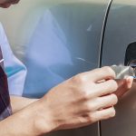 Close-up Of Person's Young Man Locksmith Hand Opening Bronze Car